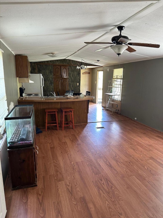 kitchen featuring ceiling fan, kitchen peninsula, hardwood / wood-style floors, and a breakfast bar area