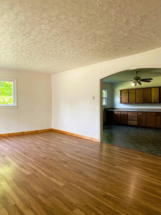 empty room with ceiling fan, dark wood-type flooring, and a wealth of natural light