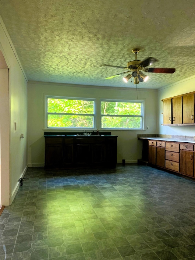 kitchen with a textured ceiling, ceiling fan, and sink