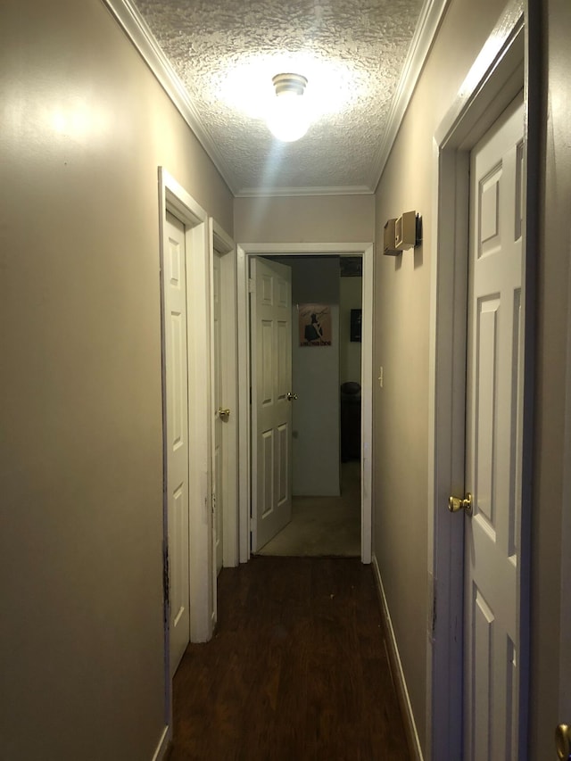 corridor with dark wood-type flooring, ornamental molding, and a textured ceiling