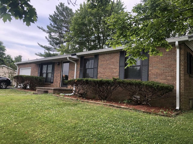 single story home featuring a garage, brick siding, and a front yard