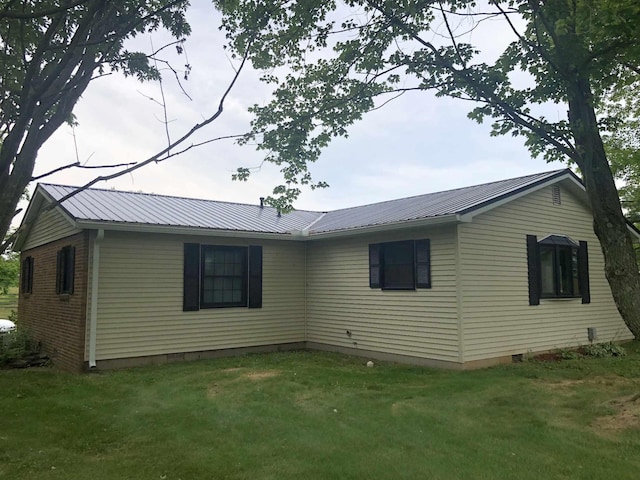 back of house with metal roof, brick siding, a lawn, and crawl space