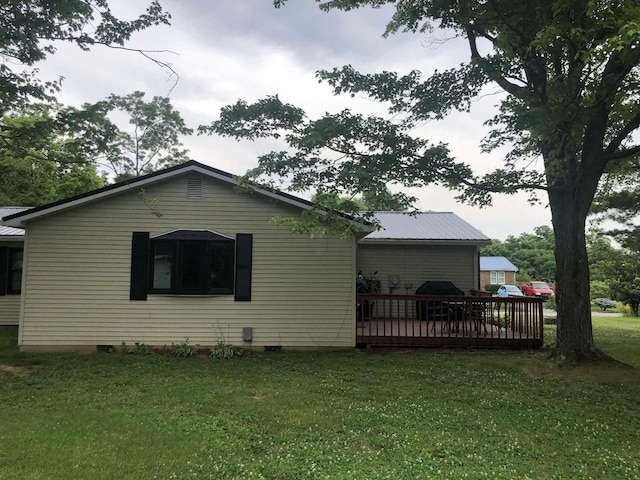 view of property exterior featuring crawl space, a yard, a wooden deck, and metal roof