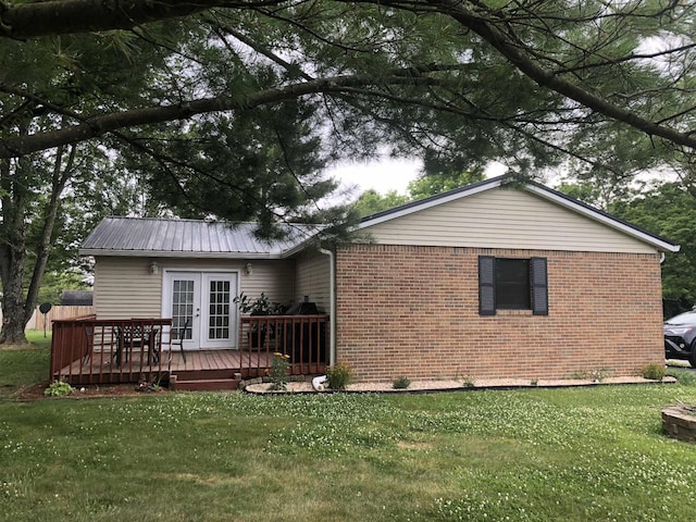 rear view of property with a wooden deck and a lawn