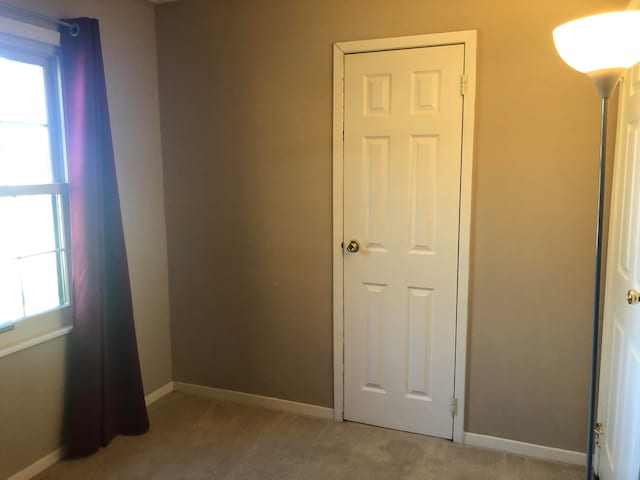 unfurnished bedroom with baseboards and light colored carpet