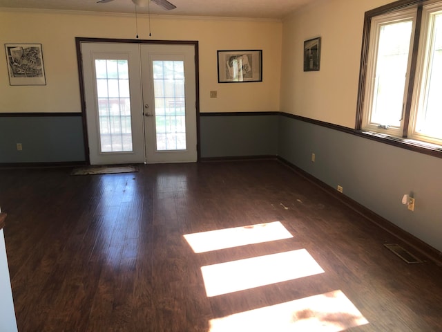 empty room featuring ornamental molding, wood finished floors, visible vents, and a healthy amount of sunlight