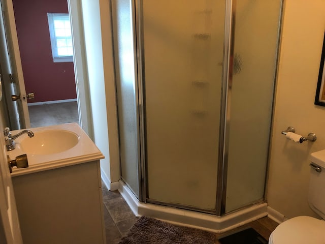 full bathroom with toilet, a shower stall, baseboards, and vanity