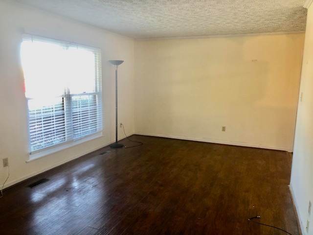 unfurnished room with a textured ceiling and dark wood-type flooring