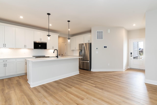 kitchen featuring stainless steel refrigerator with ice dispenser, white cabinetry, a kitchen island with sink, and pendant lighting