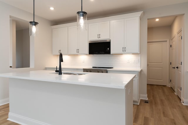 kitchen featuring a kitchen island with sink and decorative light fixtures