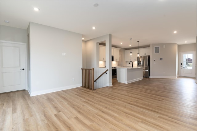 unfurnished living room with sink and light wood-type flooring