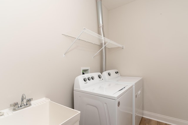 laundry room featuring wood-type flooring, sink, and washer and dryer