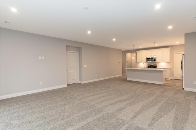 unfurnished living room featuring light carpet and sink