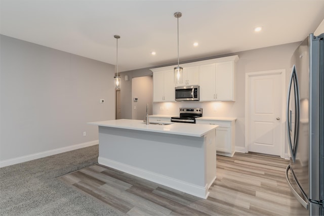 kitchen featuring a kitchen island with sink, decorative light fixtures, stainless steel appliances, and white cabinetry