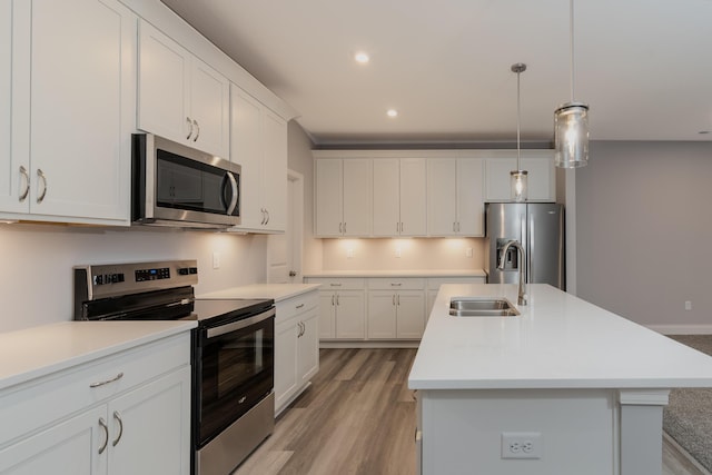 kitchen featuring stainless steel appliances, sink, a kitchen island with sink, and white cabinets