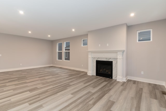 unfurnished living room featuring a high end fireplace and light wood-type flooring