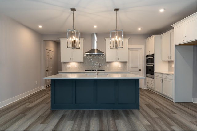 kitchen featuring white cabinets, dark hardwood / wood-style floors, wall chimney range hood, and hanging light fixtures