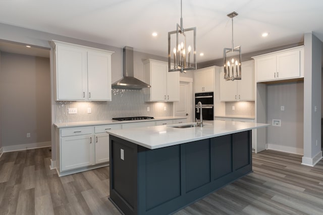 kitchen with white cabinets, decorative light fixtures, gas cooktop, and wall chimney range hood