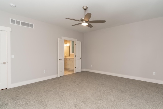 unfurnished bedroom with carpet flooring, ensuite bathroom, and ceiling fan