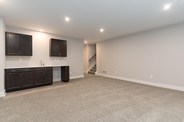 unfurnished living room featuring sink and light carpet