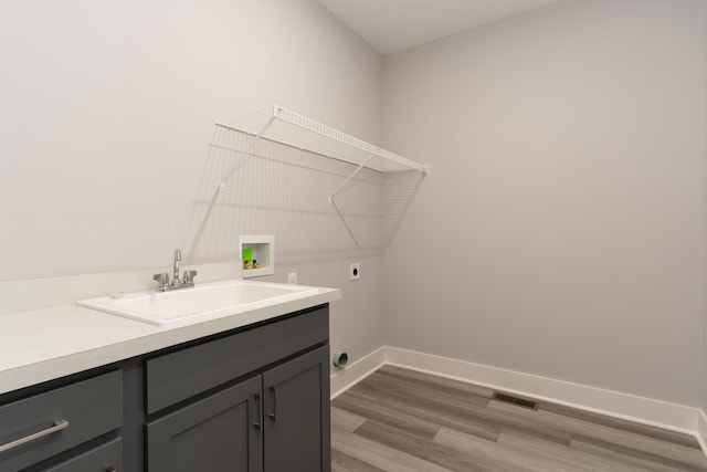 clothes washing area featuring sink, cabinets, washer hookup, hookup for an electric dryer, and light wood-type flooring