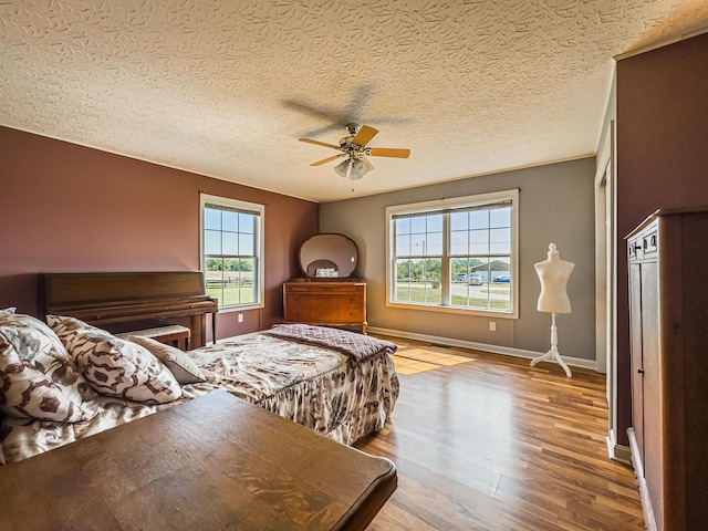 bedroom with a textured ceiling, ceiling fan, and hardwood / wood-style flooring