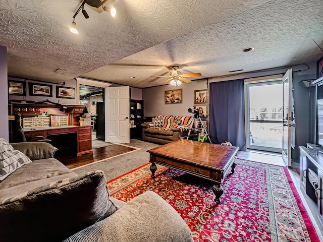 living room with hardwood / wood-style floors, track lighting, a textured ceiling, and ceiling fan