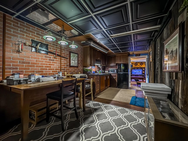 interior space with brick wall, black fridge, and dark hardwood / wood-style floors