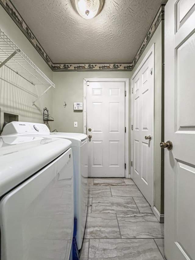 clothes washing area with a textured ceiling and washer and clothes dryer