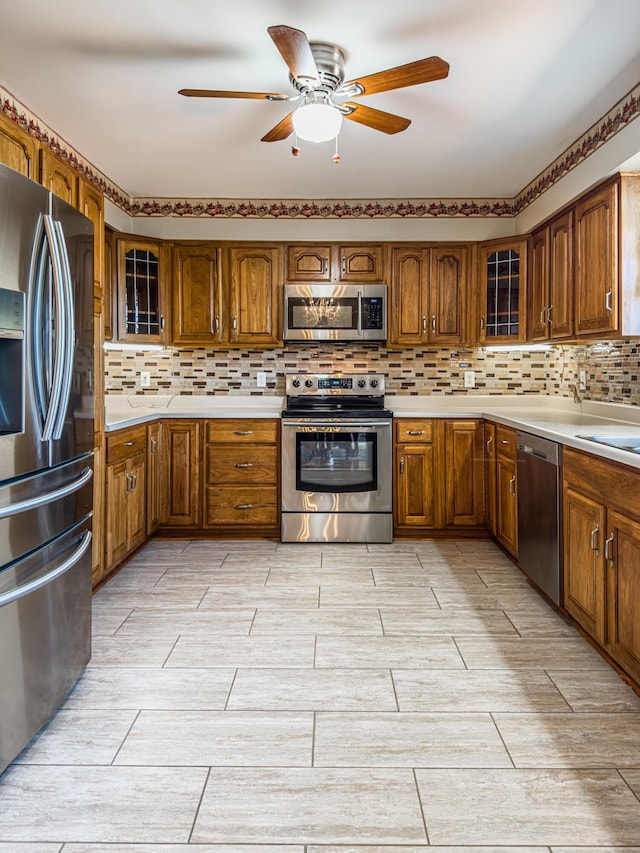 kitchen featuring ceiling fan, appliances with stainless steel finishes, and decorative backsplash