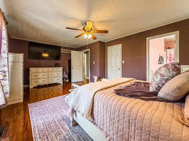 bedroom featuring connected bathroom, a textured ceiling, dark hardwood / wood-style floors, and ceiling fan