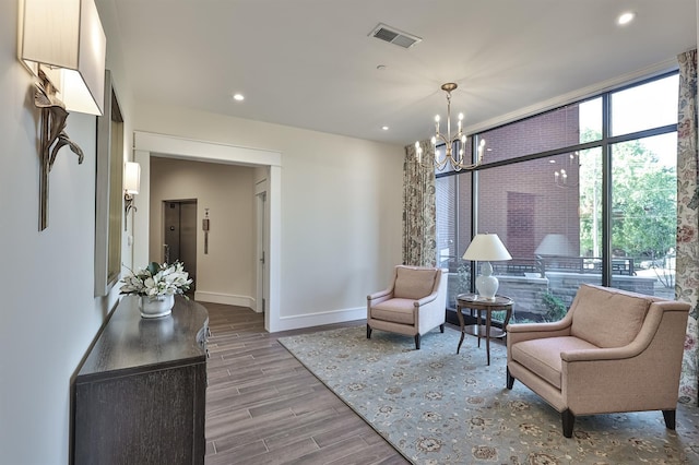 living area featuring a notable chandelier, a wall of windows, and light hardwood / wood-style flooring