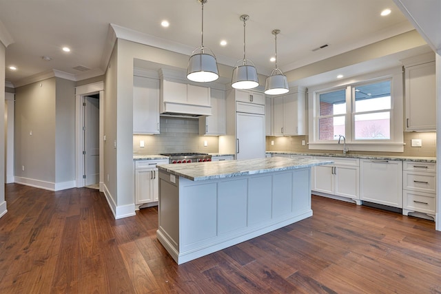 kitchen featuring a kitchen island, light stone counters, pendant lighting, and white cabinetry