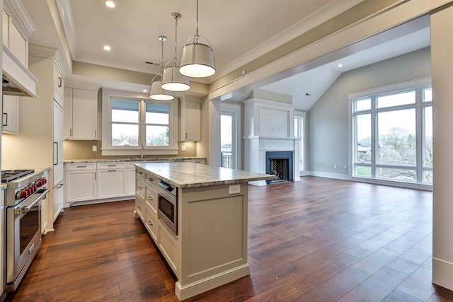 kitchen with appliances with stainless steel finishes, pendant lighting, light stone counters, a kitchen island, and white cabinets