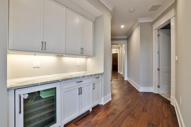 bar featuring light stone counters, dark wood-type flooring, wine cooler, white cabinets, and ornamental molding