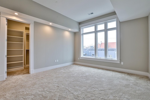 unfurnished room with light colored carpet and a wealth of natural light