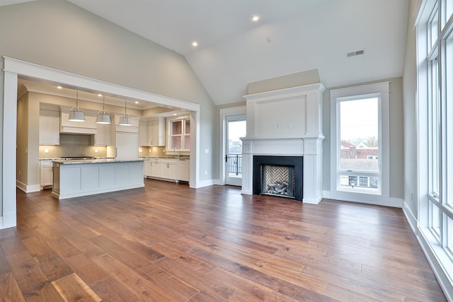 unfurnished living room featuring sink, dark hardwood / wood-style flooring, and high vaulted ceiling