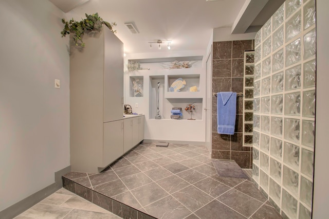 bathroom with tiled shower and vanity