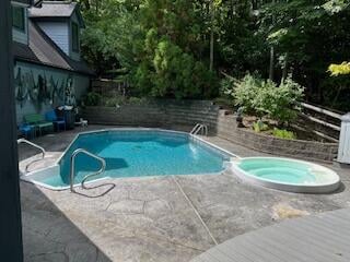 view of pool featuring a patio and an in ground hot tub