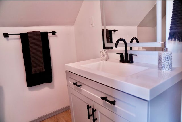 bathroom featuring vanity, lofted ceiling, and hardwood / wood-style flooring