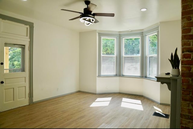 interior space featuring brick wall, light wood-type flooring, and ceiling fan