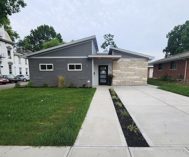 view of front of property featuring stone siding, brick siding, and a front lawn