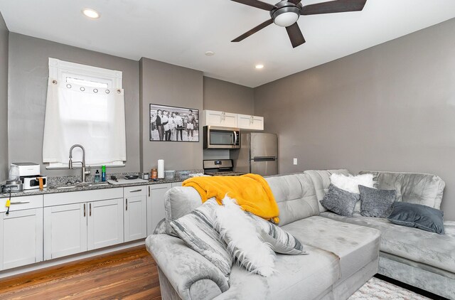 living room with dark hardwood / wood-style flooring, sink, and ceiling fan