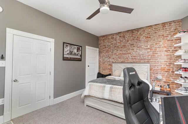 carpeted bedroom featuring brick wall and ceiling fan