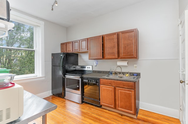 kitchen featuring light hardwood / wood-style floors, black appliances, track lighting, and sink