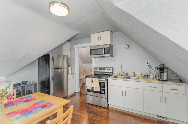 kitchen featuring lofted ceiling, white cabinets, dark hardwood / wood-style flooring, stainless steel appliances, and sink