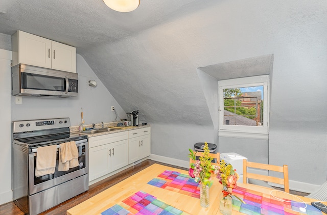 kitchen with appliances with stainless steel finishes, sink, light wood-type flooring, lofted ceiling, and white cabinetry