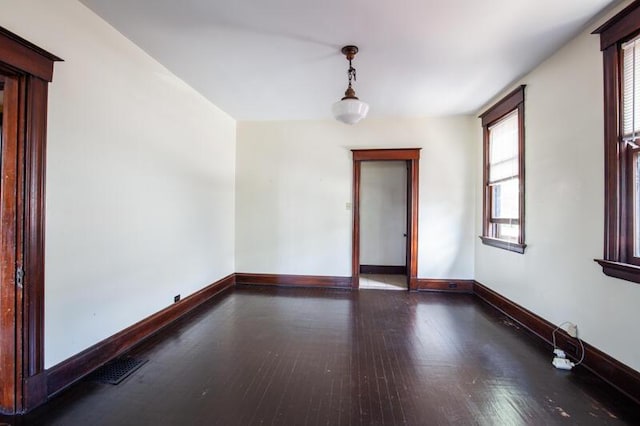 unfurnished room featuring wood-type flooring, visible vents, and baseboards