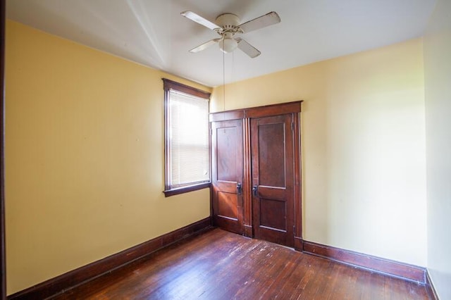 unfurnished bedroom with ceiling fan, baseboards, and dark wood-style flooring