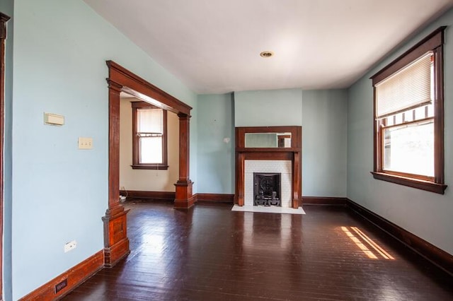 unfurnished living room with a fireplace, baseboards, and wood finished floors